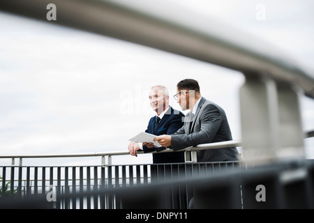 Mature businessmen standing on bridge talking, Mannheim, Germany Stock Photo