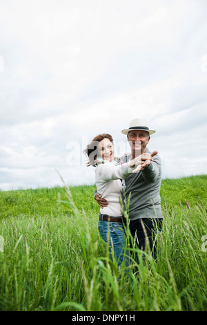 Mature couple dancing in field of grass, smiling at camera, Germany Stock Photo