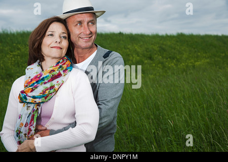 Close-up portrait of mature couple standing in field of grass, embracing, Germany Stock Photo