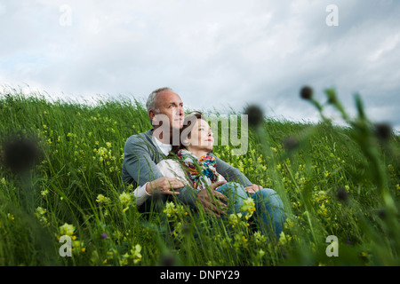Mature couple sitting in field of grass, embracing, Germany Stock Photo