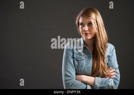 Portrait of young woman with long, blond hair, studio shot on grey background Stock Photo