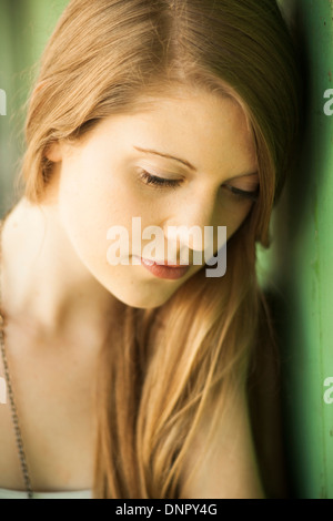 Close-up portrait of young woman with long hair outdoors, looking downwards Stock Photo