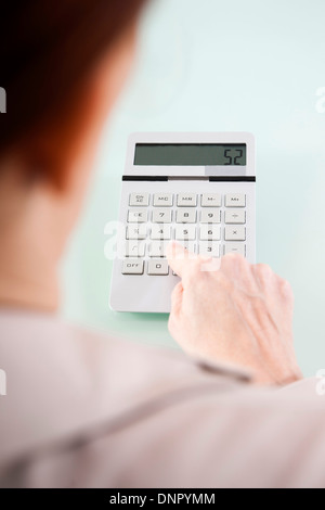 Over the Shoulder View of Mature Woman using Calculator in Office Stock Photo