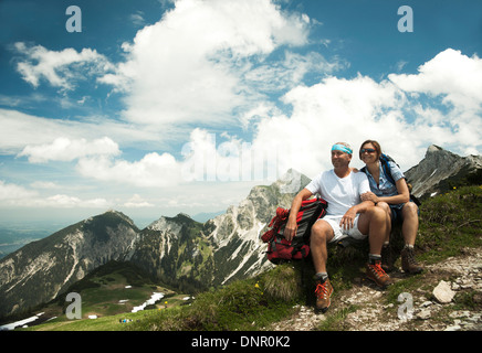 Mature couple sitting on grass, hiking in mountains, Tannheim Valley, Austria Stock Photo