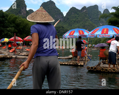 Woman guiding traditional bamboo raft on Li River near Yangshuo and Guilin, Guangxi, China. Stock Photo