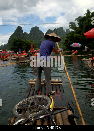 Woman guiding traditional bamboo raft on Li River near Yangshuo and Guilin, Guangxi, China. Stock Photo