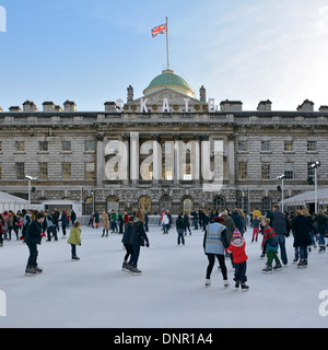 Adults & kids ice skaters with backdrop historical Somerset House building & courtyard on temporary winter ice skating rink Strand London England UK Stock Photo