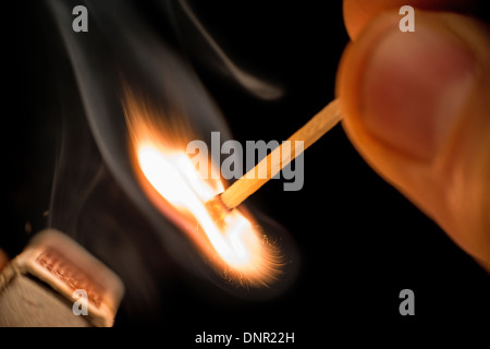 Fire from match in darkness. Hand holding match Stock Photo