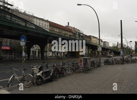 Grey sky view pavement railings motor-scooter, bicycles, to elevated U-Bahn railway, Schonhauser Allee at Kastanienallee, Berlin Stock Photo