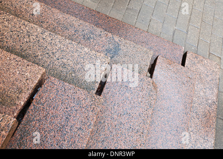 Old stairs made of red granite on gray pavement Stock Photo
