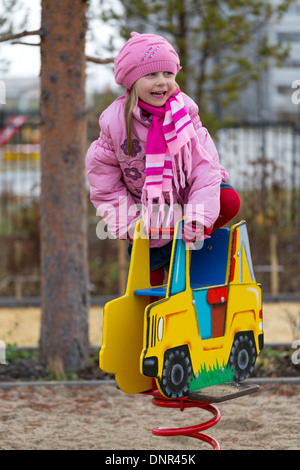 Little girl on the carousel in the autumn clothes. Stock Photo