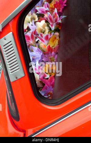 Silk flowers in the back of orange car / Garlands in car Stock Photo