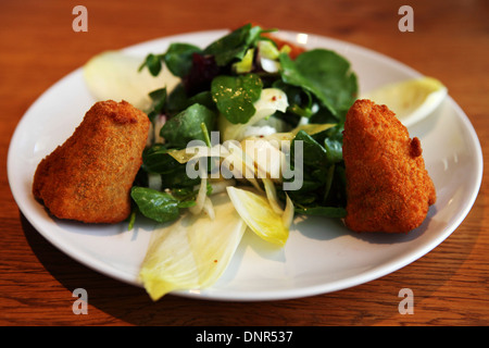 Deep fried, breaded Camembert cheese served with salad. The dish is an example of modern French cuisine. Stock Photo