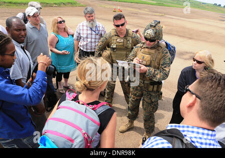 A US Marine from the Crisis Response team guides American citizens to an evacuation flight January 3, 2014 in Juba, South Sudan. The Marines evacuated more than 20 personnel from the U.S. Embassy as conflict escalates in South Sudan following a failed coup attempt. Stock Photo