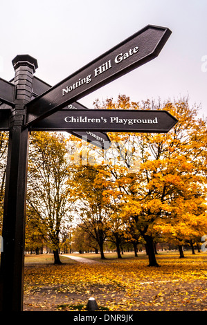 Black metal signpost to Notting Hill Gate and Children's playground, in Kensington Gardens, London. Stock Photo