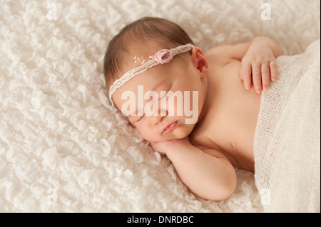 Sleeping newborn baby girl wearing a lace headband. Stock Photo