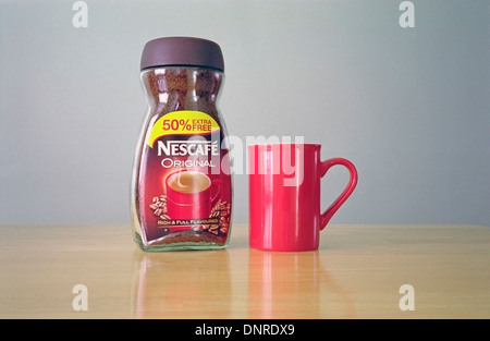 Jar of Nescafe Instant Coffee Granules with a Red Mug Stock Photo