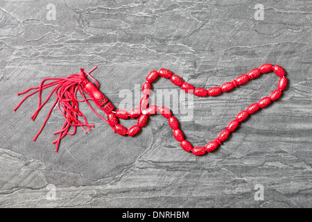 Red islamic prayer beads on a grey surface Stock Photo