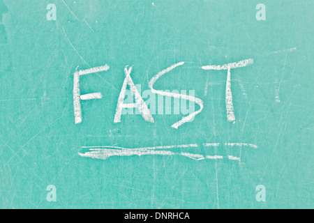 Fast written in white chalk on a green board Stock Photo