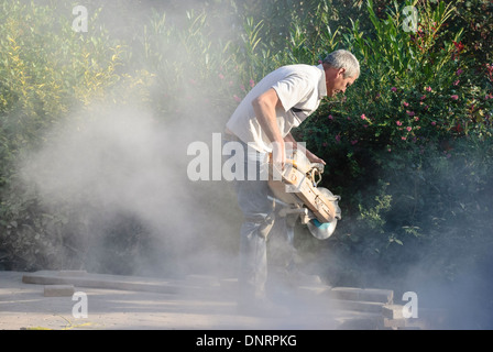 A builder uses an angle grinder to cut bricks while laying a patio Stock Photo
