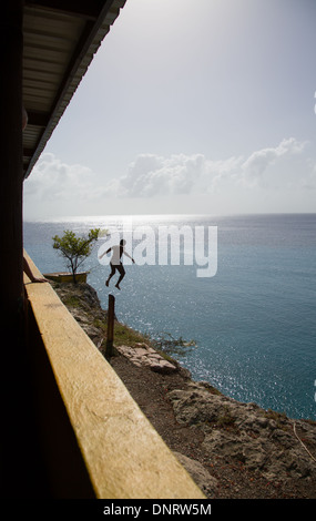 A young man jumps off into the ocean of the Caribbean island of Curacao. Stock Photo