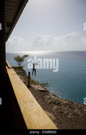 A young man jumps off into the ocean of the Caribbean island of Curacao. Stock Photo