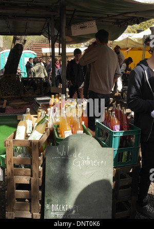 Sun shade portrait glass bottles of apple pear juice at stall selling wild gardening products, Mauer Park Flea Market, Berlin Stock Photo