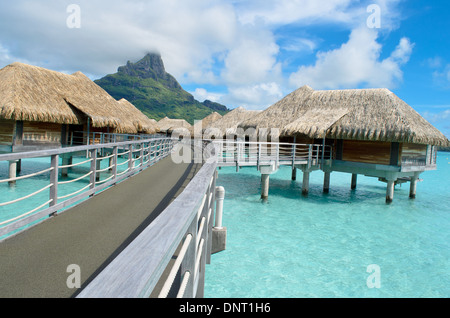 Luxury overwater bungalows in a vacation resort in the clear blue lagoon with a view on the tropical island of Bora Bora. Stock Photo