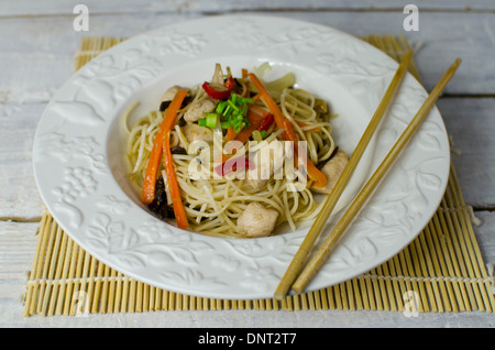 Chow mein noodles with chicken, mushrooms, carrots and onions on a withe plate Stock Photo