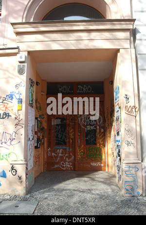 Sunny portrait graffiti scrawl painted masonry recess and closed brown doors of apartment block 6, Fehrbelliner Strasse, Berlin Stock Photo