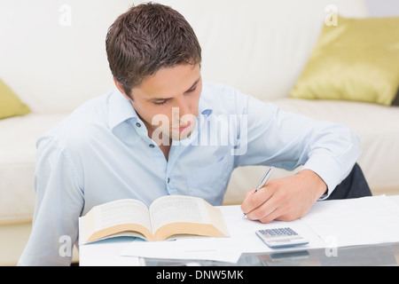 Man with bills and calculator in living room Stock Photo