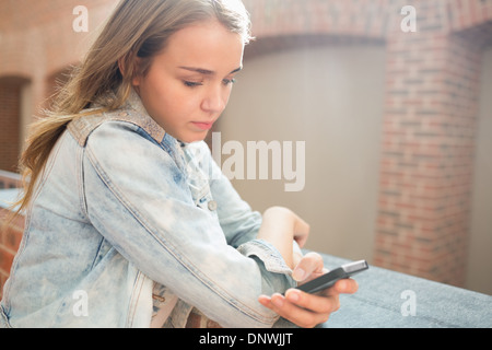 Serious student standing in the hall sending a text Stock Photo