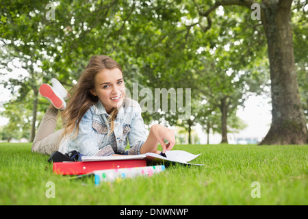 Happy young student lying on the grass studying Stock Photo