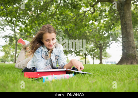 Happy student lying on the grass studying Stock Photo