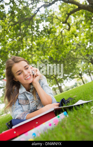 Young happy student lying on the grass on the phone Stock Photo