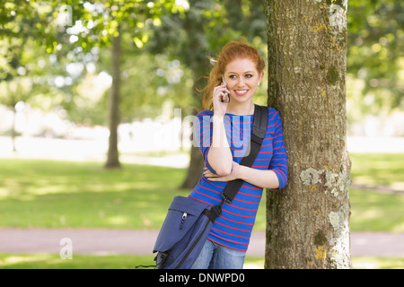Happy student leaning against a tree talking on the phone Stock Photo