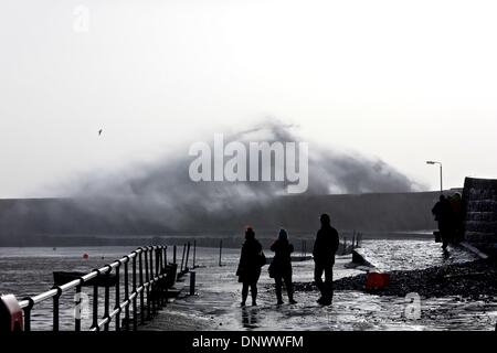 Lyme Regis, Dorset, UK, 6th January 2014: Locals watch as high winds and huge waves continue to batter the South West coast. Dorset Police warn people to stay away from coastal areas in wet and windy conditions. Credit:  Tom Corban/Alamy Live News Stock Photo