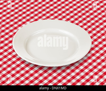 white plate over red checked picnic tablecloth Stock Photo