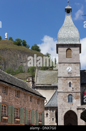 Murat, Cantal, Auvergne, France - 9 Aug 2013: A statue of Virgin Mary above a church and clock tower in the old town of Murat. Stock Photo