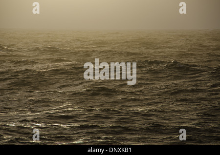 A passing rain squall captures the dusk light on relatively calm waters of Drake Passage in the Southern Ocean between South America and Antarctica. Stock Photo