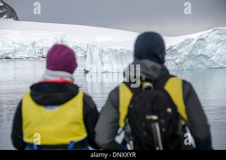 ANTARCTICA - Passengers ready in their life vests admire the view of the landscape while waiting to board Zodiac inflatable boats to go ashore at Cuverville Island on the western side of the Antarctic Peninsula. Stock Photo