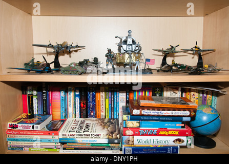 A young boy's precious toys, aeroplane models and books neatly displayed on a bookcase in a bedroom Stock Photo