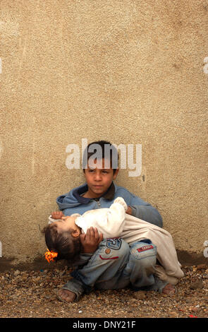 Jan 12, 2006; Abu Ghraib, Baghdad, IRAQ; An young Iraqi boy holds his baby sister as he waits to be seen by doctors at a mobile clinic set up in a farming village near Abu Ghraib, Iraq, Jan. 12, 2006. The infant girl was diagnosed with pnuemonia and given anti-biotics. Mandatory Credit: Photo by Bill Putnam/ZUMA Press. (©) Copyright 2006 by Bill Putnam Stock Photo