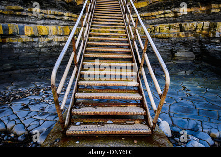 Metal stairs leading up, through Jurassic layers of limestone, at Kilve beach, Somerset. Stock Photo