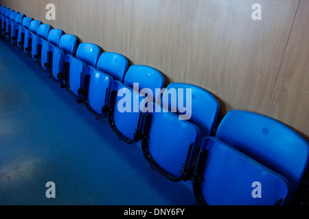 Blue folded and empty plastic seats stretched in a diagonal row. Stock Photo