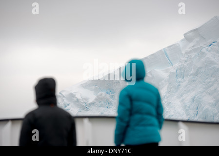 ANTARCTICA - Two passengers stand on the deck of a ship passing through the beautiful Lemaire Channel on the western side of the Antarctic Peninsula. The Lemaire Channel is sometimes referred to as 'Kodak Gap' in a nod to its famously scenic views. Stock Photo