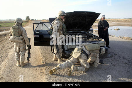 Jan 22, 2006; Saqlawiyah, IRAQ; Members of a unit from Golf Company, Second battalion, 6th Marines, RCT-8 examine a car that they had just shot after the Iraqi man driving ignored orders (first by waving a stop flag, and secondly by popping colored smoke) by the marines to stop his vehicle as he approached them at speed. The marines then resorted to the third step of their 'escalat Stock Photo