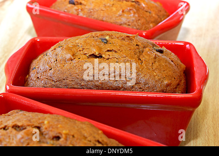 pumpkin chocolate chip bread in red loaf pans cooling on a kitchen table right out of the oven Stock Photo