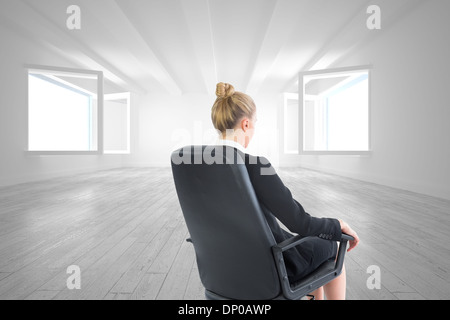 Composite image of businesswoman sitting on swivel chair in black suit Stock Photo