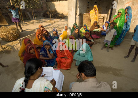 Mar 07, 2006; Anantpur village, Uttar-Pradesh, INDIA; A CASHPOR Micro Credit employee, Basant (man sitting with paperwork, a Center Manager) collects a bank deposit slip, checks clients' attendence, and dicsusses problems on his weekly visit to a remote village where a group of clients qualified for micro loans. The woman sitting next to Basant is Subnam, his supervisor (Manager of Stock Photo